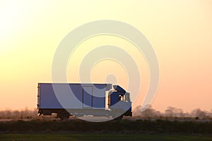 Cargo truck driving on highway hauling goods in evening. Delivery transportation and logistics concept