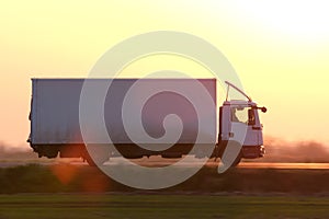 Cargo truck driving on highway hauling goods in evening. Delivery transportation and logistics concept