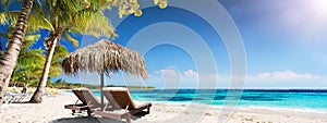 Caribbean Palm Beach With Wooden Chairs And Straw Umbrella