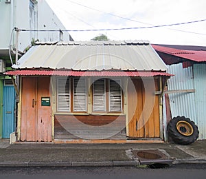 Caribbean wooden house with orange doors, tin roof and closed white window shutters. Caribbean architecture photo