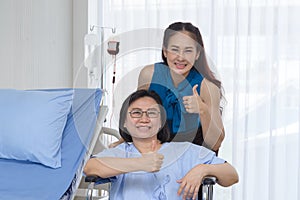 Caring adult daughter taking care her senior mother in wheelchair while visiting doctor