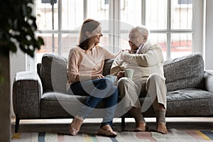 Caring adult daughter talking drinking tea with old father