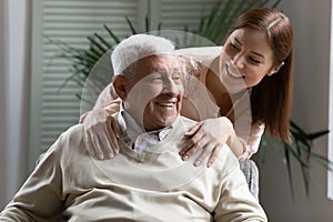 Caring adult granddaughter hugging elderly 80s grandfather