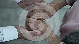 Caring adult son holding mother hands, meeting in nursing home park, family