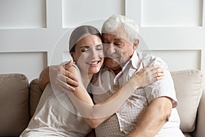 Caring adult young woman cuddling happy older hoary father.