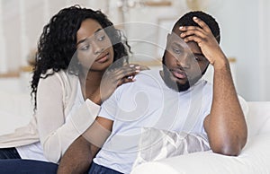 Young african woman comforting her upset boyfriend photo