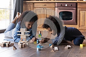 Caring African American mother and daughter playing with wooden blocks