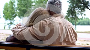Caring aged husband hugging wife, sitting on park bench, relations tenderness