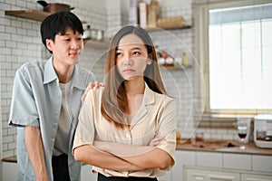 Caring Asian boyfriend is trying to comfort his angry girlfriend in the kitchen. showing care