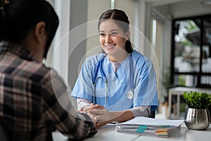 A caring Asian female doctor holds a patient\'s hands to reassure and comfort her feelings