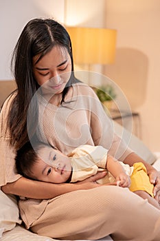 A caring Asian mom is putting her little son to sleep in her arms. napping and bedtime