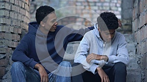 Caring black male trying to comfort upset friend, puberty age misunderstanding