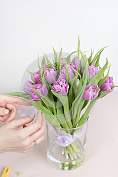Caring for a bouquet of flowers, step by step. Cut the stems and put in a vase. Young woman holding a beautiful bunch of