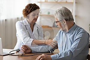 Caucasian male doctor measure blood pressure of mature patient