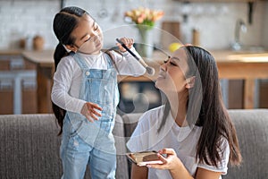 Caring child applying the compact powder to her female parent