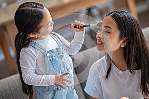 Caring child powdering her female parent forehead