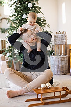 Caring dad holding baby on neck at home with festive decor