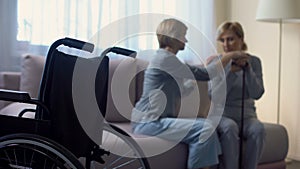 Caring daughter talking with disabled senior mother at home, rehabilitation