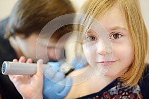 A caring doctor checks moles on the skin of a small child. A dermatologist looks at a rash on the back of a girl using a