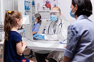 Caring doctor discussing symptoms with mother in medical clinic