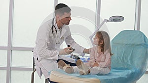 A caring doctor examines a little girl's ear using a special device.