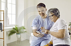 Caring doctor helping senior woman to use a health monitoring app on her smartphone