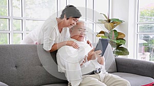 Caring elderly 60s wife caress hug middle-aged husband bring blanket with blanket at home. Happy old mature couple relax enjoy