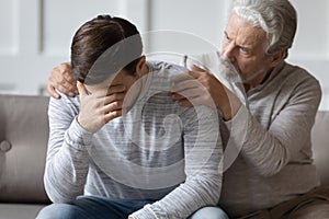 Caring elderly father comfort upset adult son