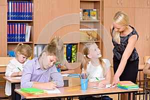 Caring elementary school teacher helping student in classroom