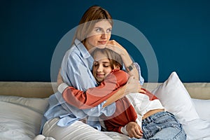 Caring empathic young mom affectionately cuddling calming upset depressed teen daughter.