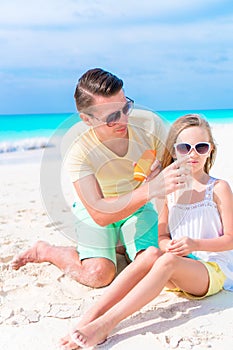 Caring father applying sun cream to daughter nose on the beach. The concept of protection from ultraviolet radiation