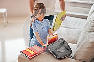 Caring father helping his little son pack a school-bag