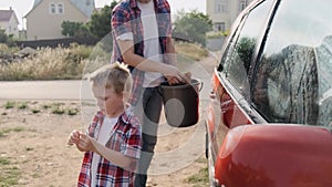 Caring father teaches his small baby boy how to wash their car slow motion