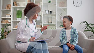 Caring female baby doctor having appointment with little boy in medical office.
