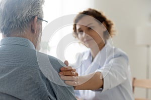 Caring female doctor comfort senior male patient at consultation