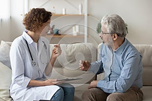 Caring female doctor consult elderly patient at home