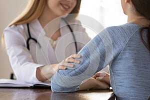 Caring female doctor comforting young woman patient at meeting photo