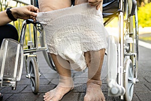 Caring female nurse assisting a elderly patient with giving diaper change,asian senior woman put nappy,disposable diaper,disabled