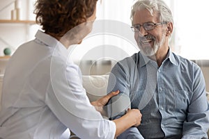 Caring female nurse measure blood pressure of senior patient