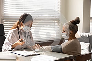 Female nurse measure blood pressure of mature patient