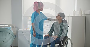 Caring female nurse talking to disabled patient in hospital