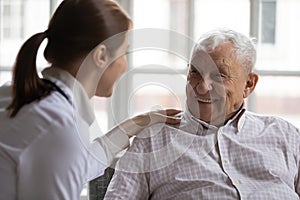 Caring geriatric nurse in white coat cares for elderly man photo
