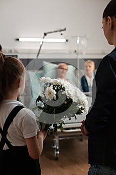 Caring granddaughter bringing flowers gift to sick old grandfather