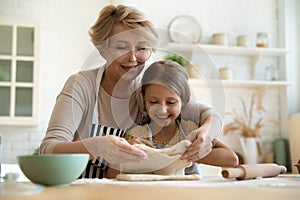 Caring grandmother baking pie with little 9s granddaughter