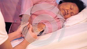 Caring hands holding old woman`s hands in bed