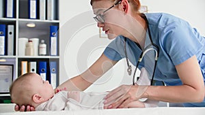 caring for health of baby, female pediatrician in glasses with a phonendoscope examines a small child in medical office