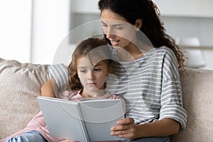 Caring Latin mom and teen daughter read book together