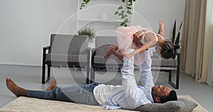 Caring loving father afro american man plays with little funny daughter girl child in pink dress like ballerina, dad