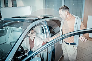 Caring loving man giving hand to his woman leaving car