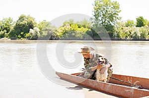 Caring male owner petting happy setter, while floating during morning fishing in sunny day.